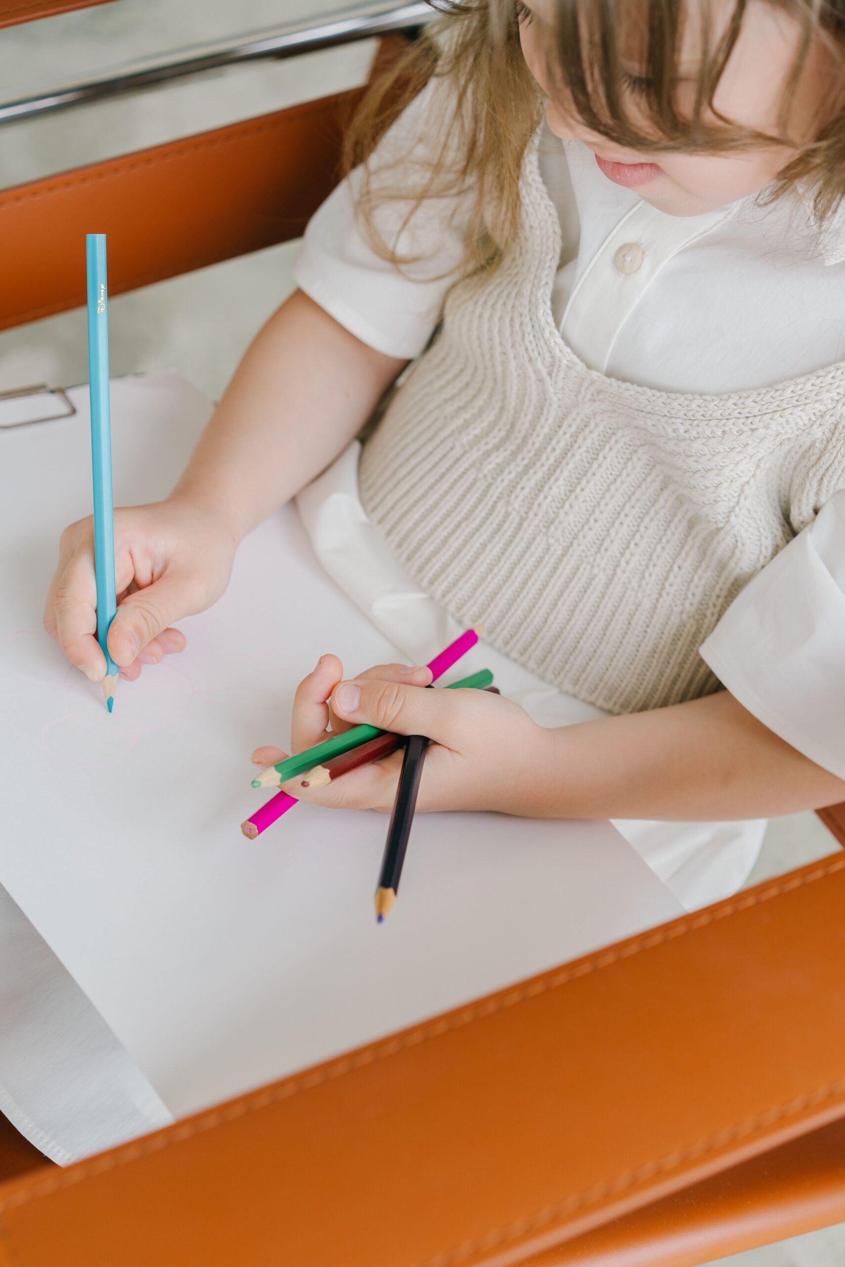 young child holding coloured pencils